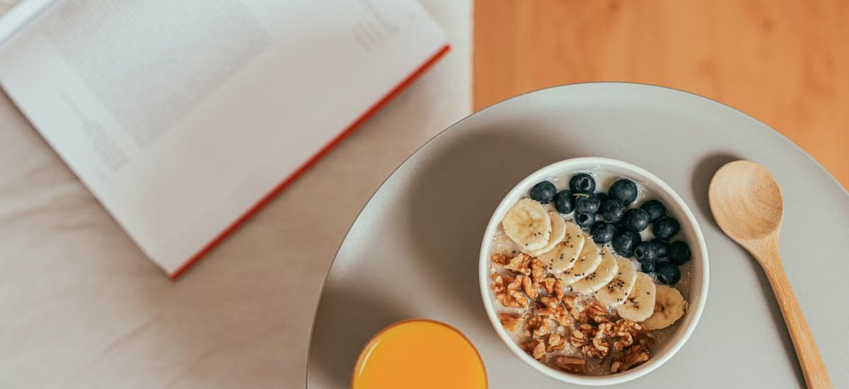 Top view of healthy breakfast with oatmeal, fresh fruit, and orange juice on a tray.